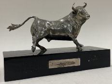 A silver figure of a bull on stand.