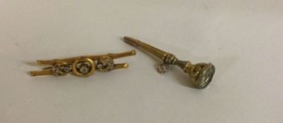A chased gold plated watch key together with a brooch.