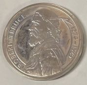A silver coin commemorating Robert The Bruce inscribed '1274 - 1329'.