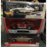 Three boxed 1:18 scale model cars.
