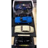 Four 1:18 scale unboxed model cars together with one other.