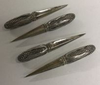 A set of four silver sweetcorn holders with handles in the form of a corn on the cob.