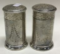 A pair of heavy silver peppers with swag decoration.