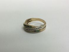 A 14 carat gold emerald and diamond crossover ring. Approx. 3 grams