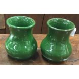 A pair of small green pottery vases.