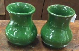 A pair of small green pottery vases.