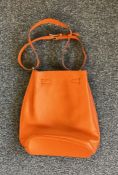 An orange leather shoulder bag in the style of the Kelly design, marked "Hermes".