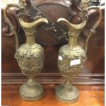 A heavy pair of brass ewers with cherub decoration.