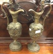 A heavy pair of brass ewers with cherub decoration.