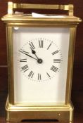 A brass carriage clock with white enamelled dial.