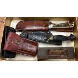 A good collection of American knives in leather sleeves.