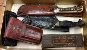 A good collection of American knives in leather sleeves.