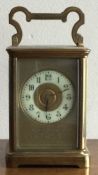 A large brass carriage clock with white enamel dial.