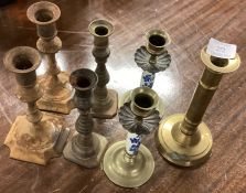 A large collection of brass candlesticks.