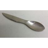 A combination silver spoon and knife.