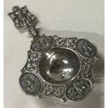 A Dutch silver tea strainer embossed with ships.