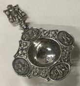 A Dutch silver tea strainer embossed with ships.