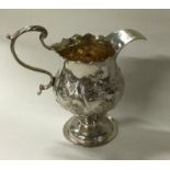An 18th Century chased cream jug. London 1767. By IS&AN.