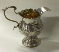 An 18th Century chased cream jug. London 1767. By IS&AN.