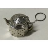 An American silver tea strainer in the form of a teapot.