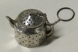An American silver tea strainer in the form of a teapot.