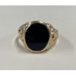 A good onyx mounted signet ring in 9 carat with scroll decoration.