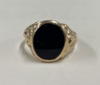 A good onyx mounted signet ring in 9 carat with scroll decoration.