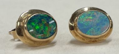 A pair of opal doublet single stone ear studs in gold mounts.