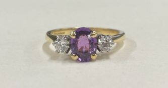 An amethyst and diamond three stone ring in 18 carat two colour gold claw mount.