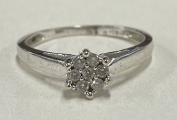 A diamond seven stone cluster ring in 18 carat gold claw mount.