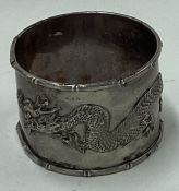 A Chinese export silver napkin ring decorated with a dragon.