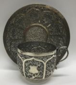 A Chinese silver cup and saucer with embossed decoration.