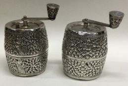 A heavy pair of cylindrical silver pepper grinders decorated with figures.