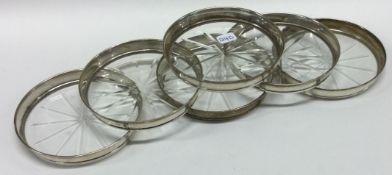 A set of six American silver and glass coasters.