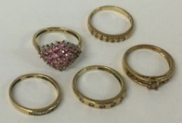 A group of five gold gem set rings.