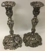 A large ornate pair of Victorian silver candlesticks embossed with flowers.