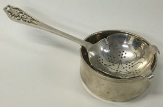 An Art Deco silver pierced tea strainer on stand.