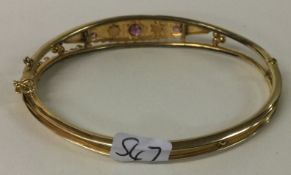 A 9 carat amethyst and diamond hinged bangle with safety chain.