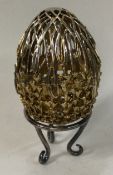 A novelty cased silver pierced egg on stand with jewelled top.