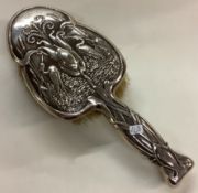 A novelty fine silver clothes brush chased with bird and plants.