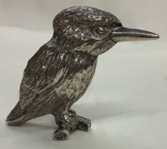 A silver plated figure of a bird on bark.