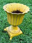 A small cast iron urn painted yellow.
