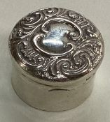 A chased silver pill box.