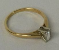 A diamond single stone baguette cut ring in two colour 18 carat gold setting.