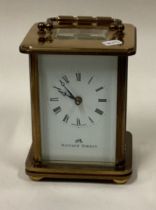 A small brass carriage clock with white enamelled dial.