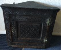 A small early oak corner cupboard with carved decoration.
