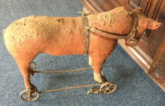 A small child's stuffed horse on wheels.