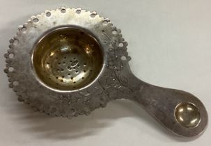 A Russian silver engraved tea strainer.