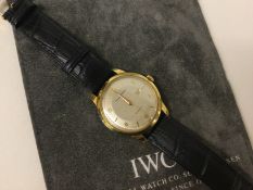 IWC (International Watch Company): An 18 carat gold wristwatch with date aperture on leather strap.
