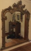 A fine quality large gilt oval mantle mirror decorated with scrolls and leaves.